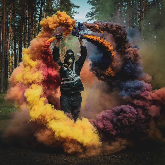 Training smoke arc in orange, purple, and blue over a pine forest