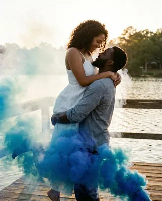 Couple celebrating a gender reveal in a cloud of colored smoke