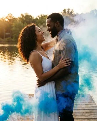 Couple celebrating a gender reveal in a cloud of colored smoke