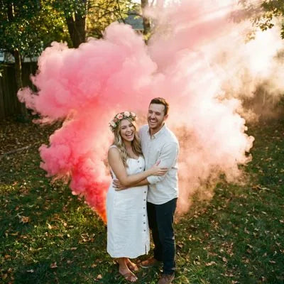Couple celebrating a gender reveal in a cloud of colored smoke