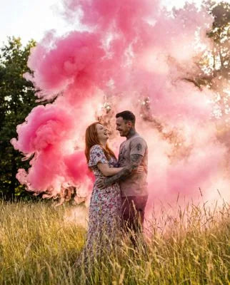 Couple celebrating a gender reveal in a cloud of colored smoke