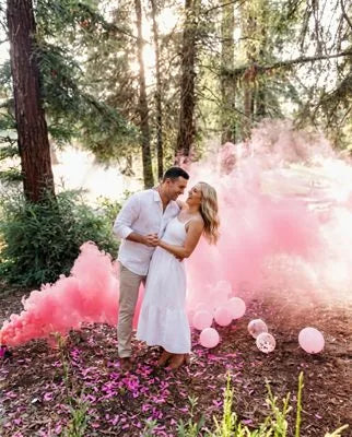 Couple celebrating a gender reveal in a cloud of colored smoke
